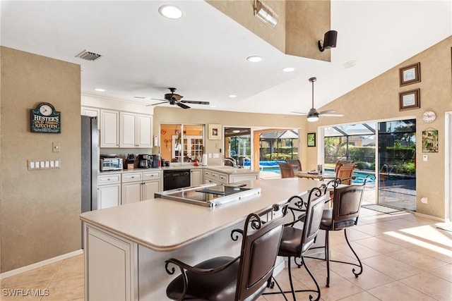 kitchen with a peninsula, a sunroom, light countertops, black appliances, and a kitchen bar