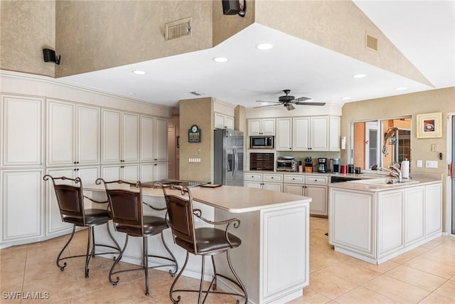 kitchen featuring visible vents, a breakfast bar, a peninsula, stainless steel appliances, and light countertops