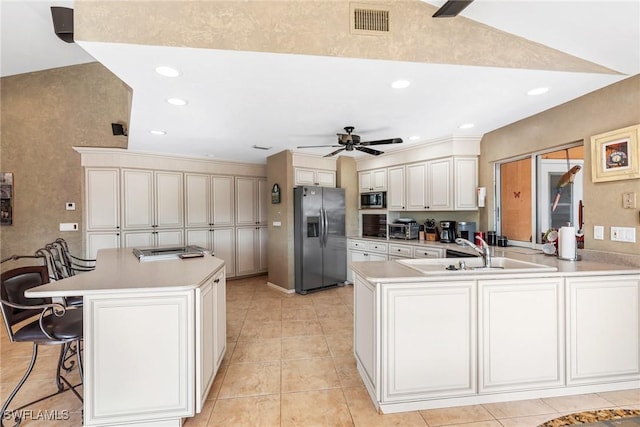 kitchen featuring a breakfast bar area, a peninsula, a sink, light countertops, and appliances with stainless steel finishes