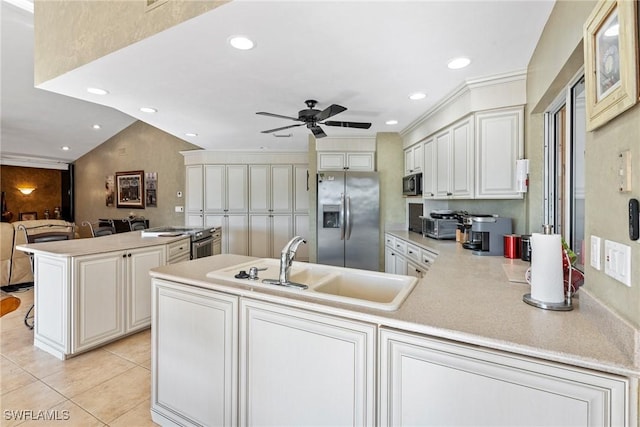 kitchen featuring stainless steel appliances, a peninsula, a sink, white cabinetry, and light countertops