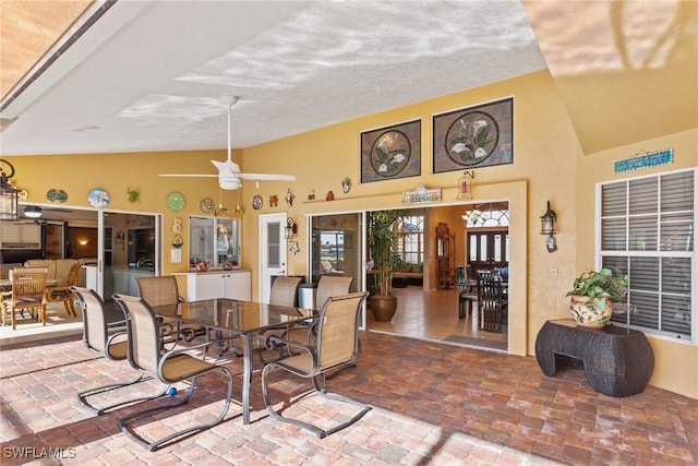 dining area featuring brick floor and high vaulted ceiling