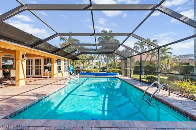 view of swimming pool with french doors, a patio area, a covered pool, and a lanai