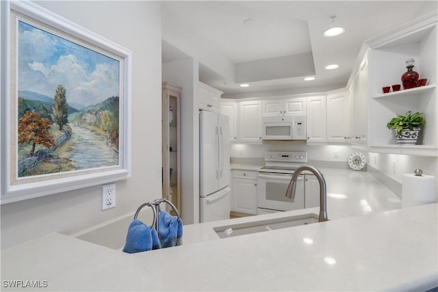 kitchen with white appliances, kitchen peninsula, and white cabinets