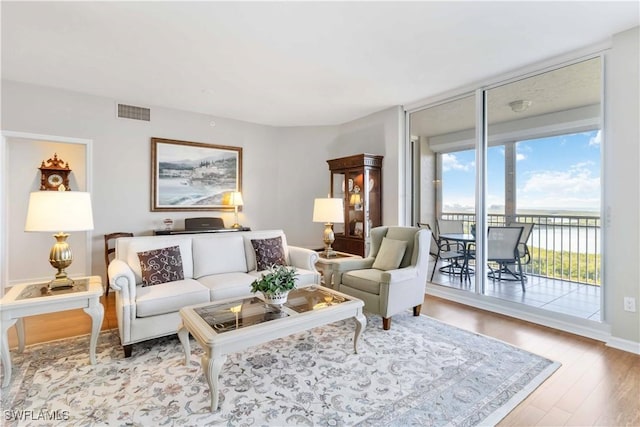 living room with light hardwood / wood-style flooring and a wall of windows