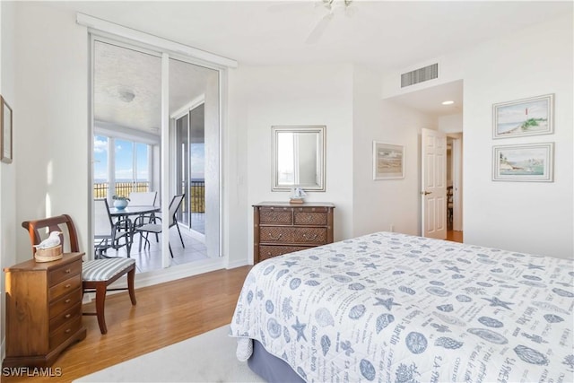 bedroom with ceiling fan, access to outside, light hardwood / wood-style floors, and a wall of windows