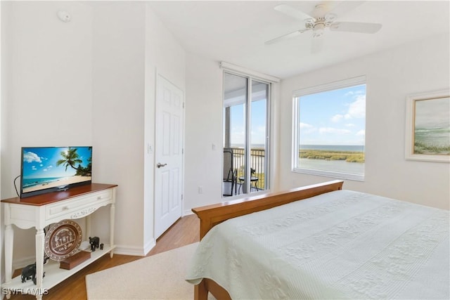 bedroom with a water view, light hardwood / wood-style flooring, ceiling fan, and access to outside