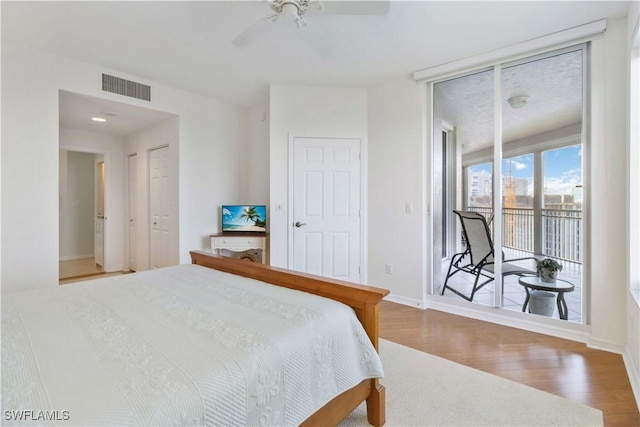 bedroom with ceiling fan, access to outside, expansive windows, and wood-type flooring