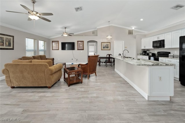 living room with ceiling fan, light hardwood / wood-style floors, vaulted ceiling, ornamental molding, and sink