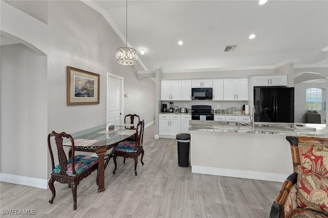 kitchen with white cabinetry, black appliances, pendant lighting, and light stone counters