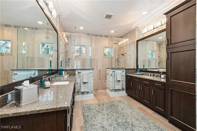 bathroom featuring tile walls, vanity, wood-type flooring, and a shower with door