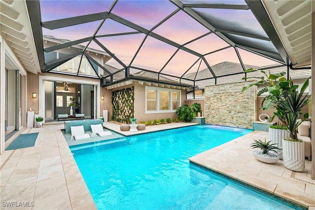 pool at dusk featuring a lanai and a patio area