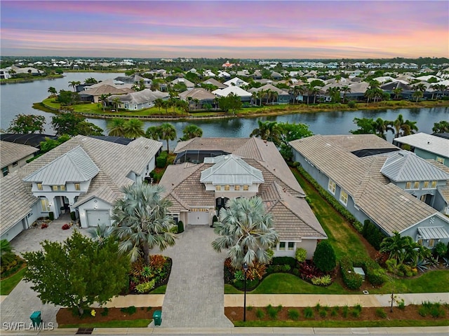 aerial view at dusk featuring a water view