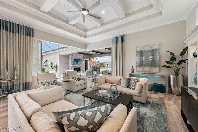 living room with coffered ceiling, a wealth of natural light, hardwood / wood-style flooring, ceiling fan, and a fireplace