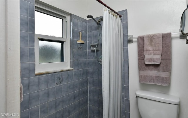 bathroom featuring toilet and curtained shower