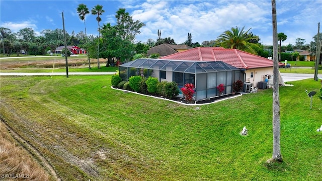 rear view of property featuring cooling unit, a lanai, and a lawn