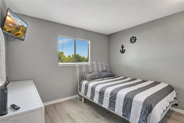 bedroom with light hardwood / wood-style floors and a textured ceiling