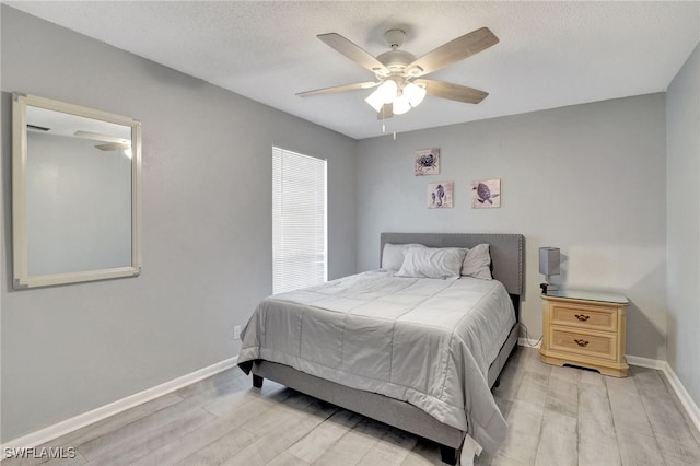 bedroom featuring ceiling fan, a textured ceiling, and light wood-type flooring