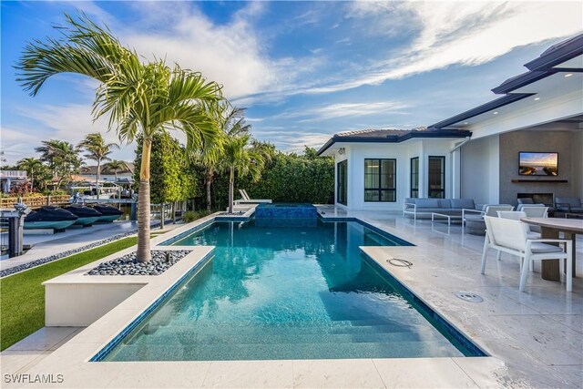 view of pool featuring a patio and an outdoor living space with a fireplace