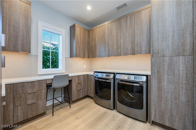 laundry area featuring cabinets, separate washer and dryer, and light hardwood / wood-style floors