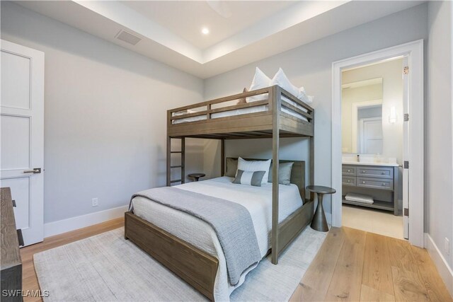 bedroom featuring connected bathroom and light wood-type flooring