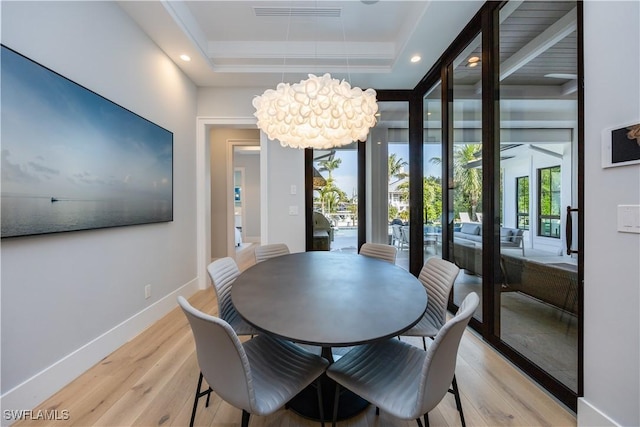 dining space featuring a tray ceiling and light hardwood / wood-style flooring