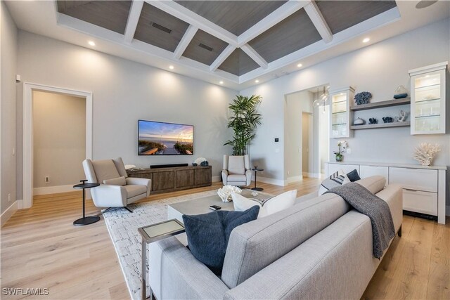 living room with a high ceiling, coffered ceiling, beam ceiling, and light hardwood / wood-style flooring