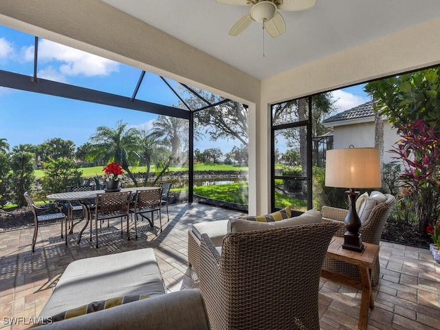 view of patio with an outdoor living space, glass enclosure, ceiling fan, and a water view