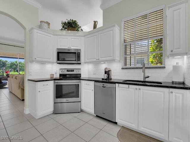 kitchen featuring sink, white cabinetry, tasteful backsplash, dark stone countertops, and appliances with stainless steel finishes