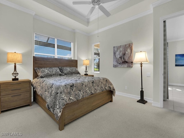 carpeted bedroom with a tray ceiling, crown molding, and ceiling fan