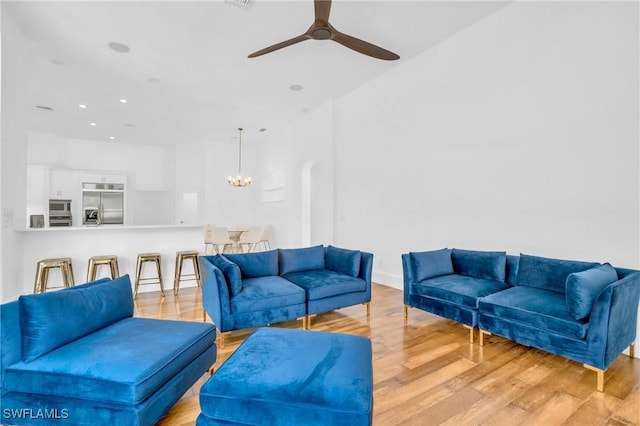 living area with recessed lighting, light wood-style flooring, and ceiling fan with notable chandelier