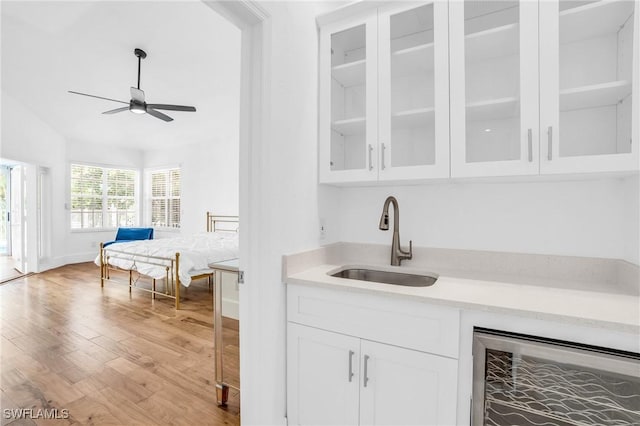 bar featuring wood finished floors, ceiling fan, wine cooler, and a sink