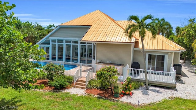 back of house with metal roof, a deck, and a fenced in pool