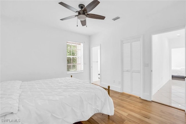 bedroom featuring a ceiling fan, baseboards, visible vents, and wood finished floors