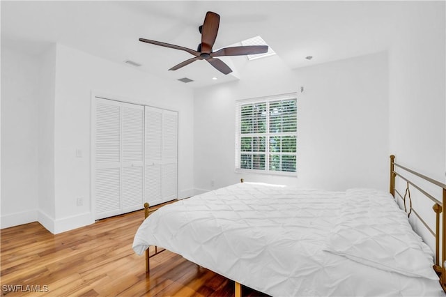 bedroom featuring a skylight, visible vents, baseboards, light wood-style floors, and a closet