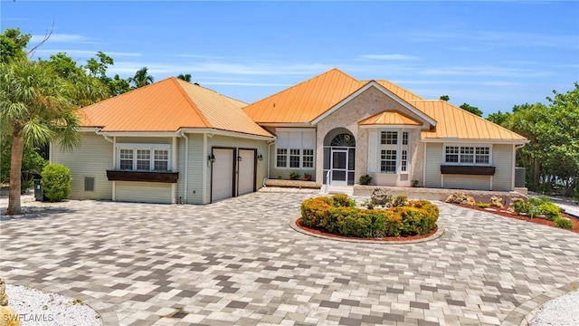 view of front of house with a garage, metal roof, and decorative driveway