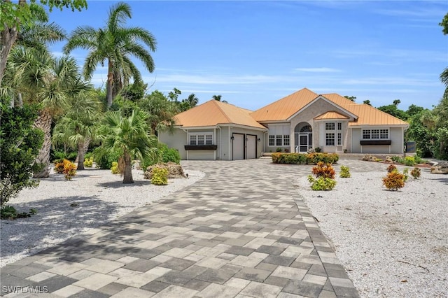 view of front of property featuring an attached garage, metal roof, and decorative driveway