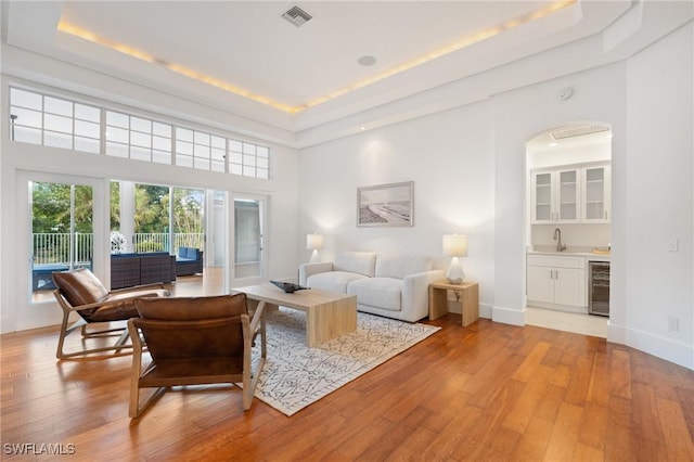 4090 W Gulf Dr, Sanibel, FL 33957 - living area with visible vents, wet bar, a tray ceiling, wine cooler, and light wood-style floors