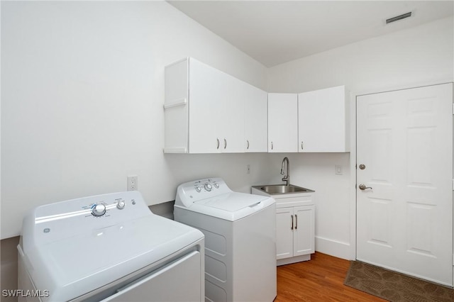 4090 W Gulf Dr, Sanibel, FL 33957 - clothes washing area with visible vents, wood finished floors, cabinet space, independent washer and dryer, and a sink