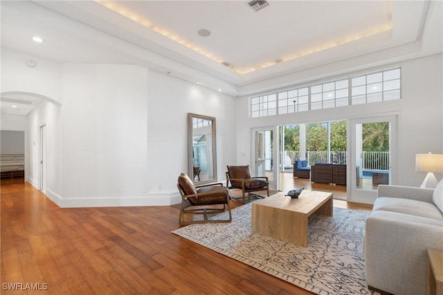 4090 W Gulf Dr, Sanibel, FL 33957 - living area with arched walkways, a raised ceiling, baseboards, and wood finished floors