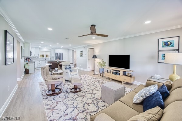 living room with crown molding, light hardwood / wood-style floors, and ceiling fan