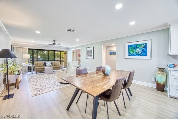 dining room with ornamental molding and light hardwood / wood-style floors