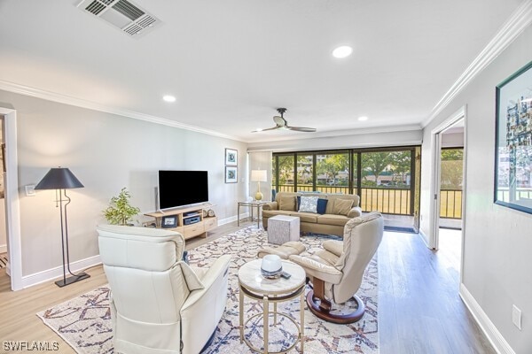 living room featuring ceiling fan, ornamental molding, and light hardwood / wood-style floors