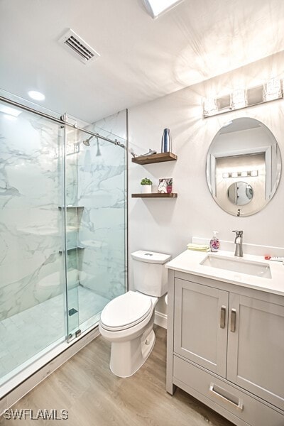 bathroom featuring hardwood / wood-style flooring, vanity, toilet, and a shower with door