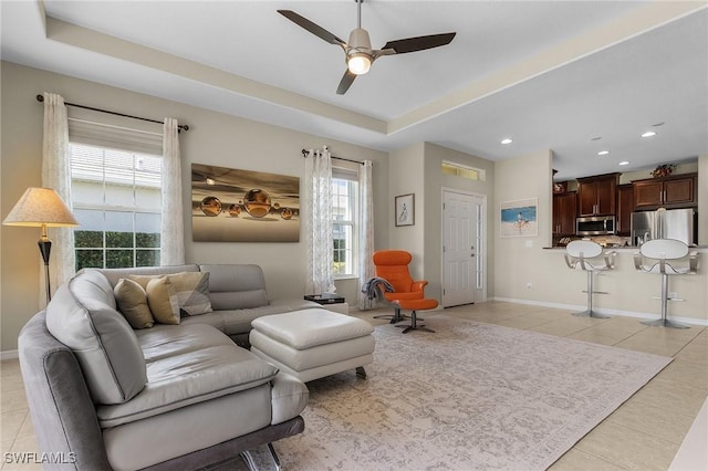 living room with a raised ceiling, a healthy amount of sunlight, and light tile patterned floors