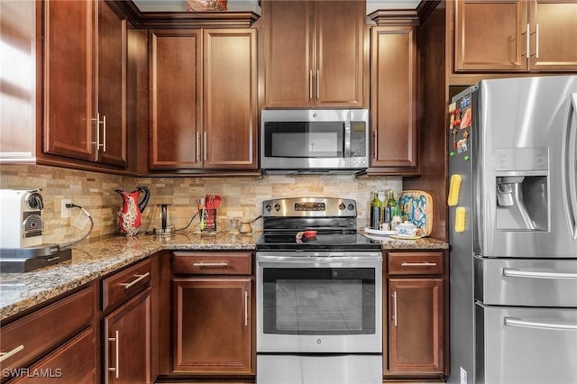 kitchen with tasteful backsplash, appliances with stainless steel finishes, and light stone counters