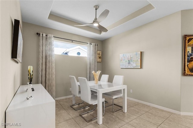 tiled dining area featuring ceiling fan and a raised ceiling