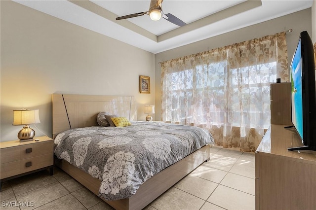 bedroom featuring ceiling fan, a raised ceiling, and light tile patterned floors