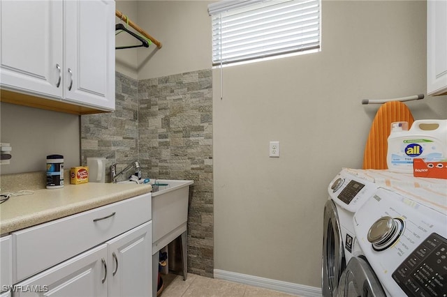 laundry area featuring washer and dryer, light tile patterned floors, and cabinets