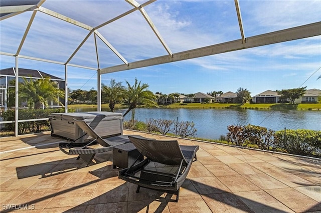 view of patio featuring a hot tub, glass enclosure, and a water view