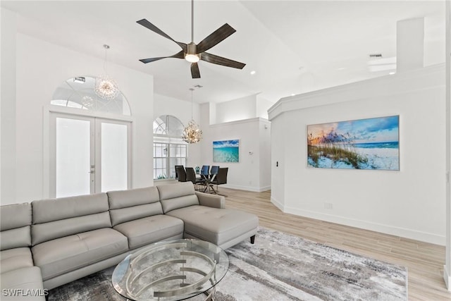 living room featuring ceiling fan with notable chandelier and light hardwood / wood-style flooring